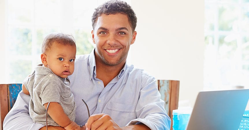 Young father with infant son smiling.