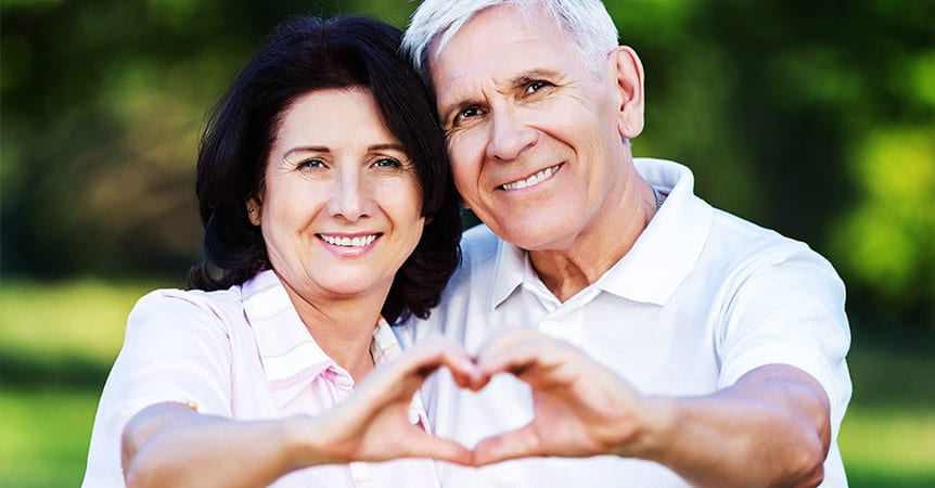 Middle aged couple holding hands out in heart shape